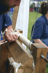 A side view of a person using a using a pole lathe