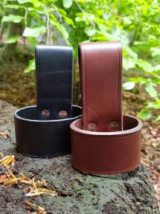 two leather axe loops in black and brown on tree stump